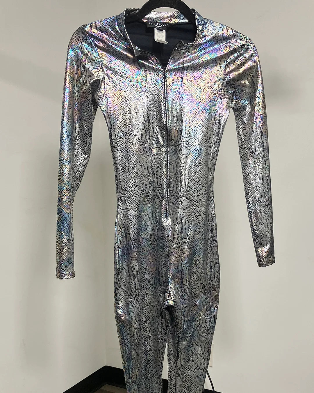 A long-sleeve, one-piece full-zip catsuit with an iridescent silver and black snakeskin pattern, displayed on a black hanger against a plain light gray wall.