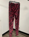 Pink and black leopard print leggings hanging on a black hanger against an off-white wall.