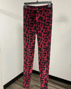 Pink and black leopard print leggings hanging on a black hanger against a plain white wall.