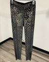 Black and beige leopard-print velvet pants hanging on a hanger against a plain indoor wall.