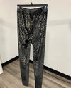 Black and gray snakeskin print leggings hanging on a black hanger against a white wall and wood floor.