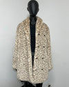 A beige and brown leopard-print faux fur coat with a wide collar, displayed on a black mannequin torso against a plain light gray wall.