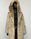 A beige and brown leopard-print faux fur coat with a large hood, displayed on a black mannequin against a plain light gray wall.