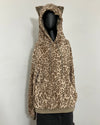 A leopard print fleece hoodie with cat ears on the hood, displayed on a black mannequin torso against a plain white wall.