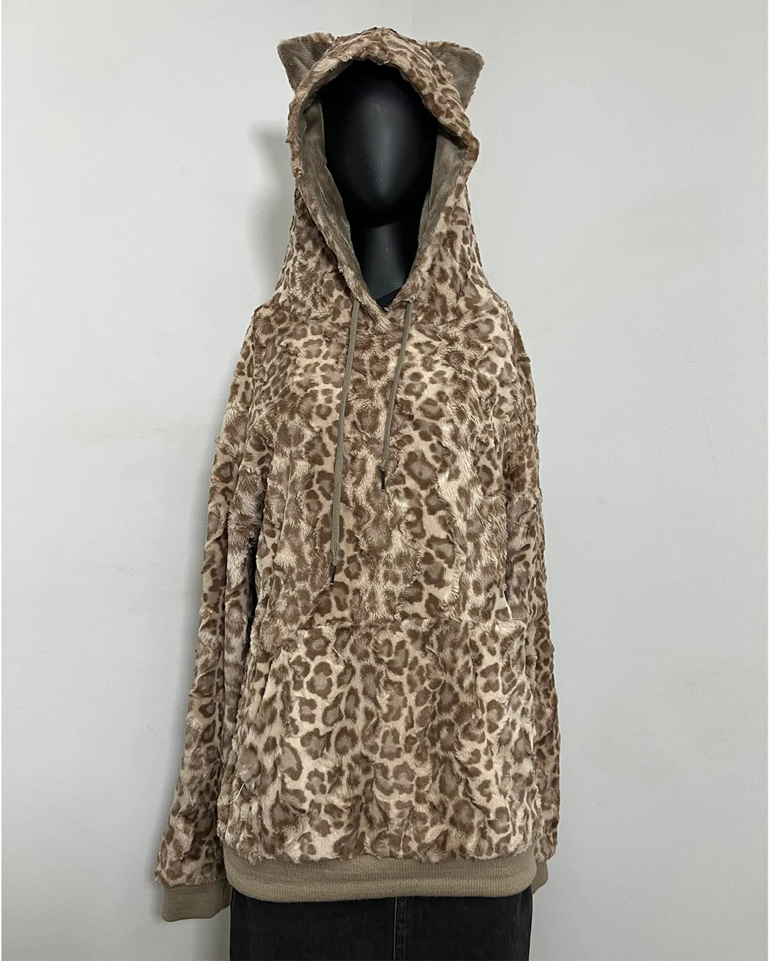 A plush faux-fur hooded sweatshirt with a brown and beige leopard print pattern, featuring cat ears on the hood, displayed on a black mannequin torso against a light gray background.