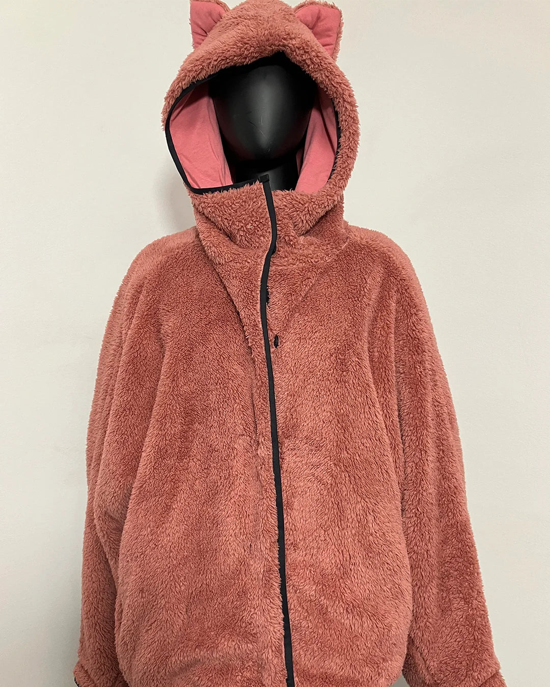 A plush teddy fleece zip-up hooded jacket with cat ears on the hood, displayed on a black mannequin against a plain off-white background.