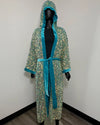 A hooded kimono robe with a dense multicolor sequin pattern and bright turquoise blue satin trim, shown on a black mannequin against a plain white wall.