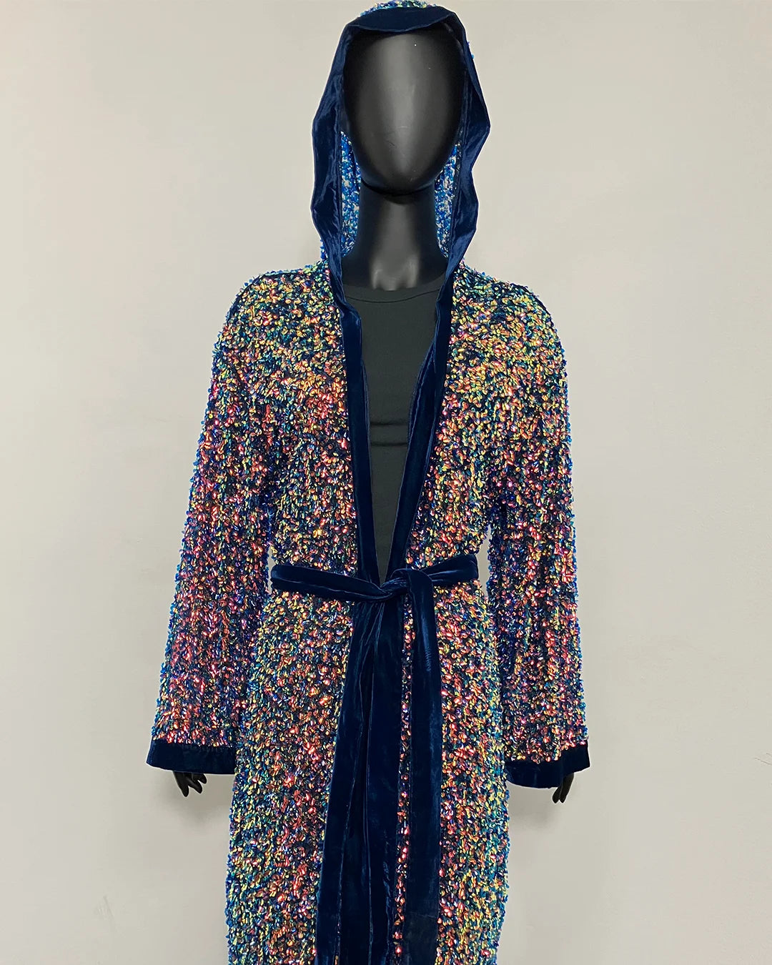 A hooded robe with multicolor sequins and dark blue velvet trim, displayed on a black mannequin against a plain light background.