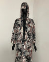 A hooded long-sleeve robe with an all-over abstract floral and botanical print in black, white, and muted red, displayed on a black mannequin against a plain light gray wall.