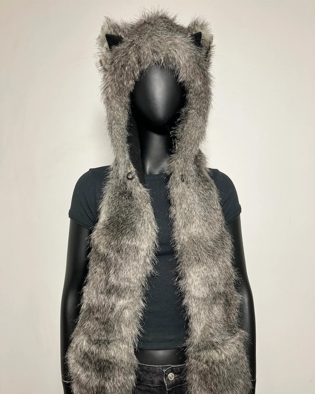 A gray faux fur hooded vest with long ears, displayed on a black mannequin torso against a plain off-white background.