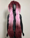A shaggy, long faux-fur style accessory displayed on a black mannequin torso against a plain light wall. The item has a dark burgundy top section that fades into bright pink at the bottom, resembling ombre hair or fabric.