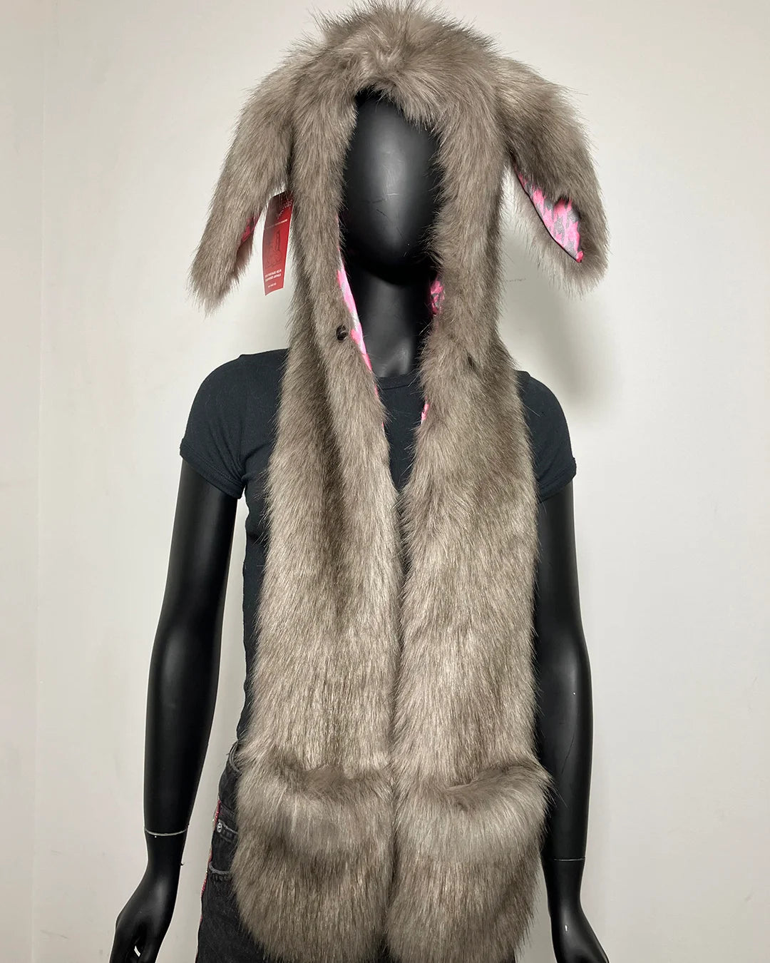 A gray faux fur hood with long bunny ears on the hood, displayed on a black mannequin against a plain light background.