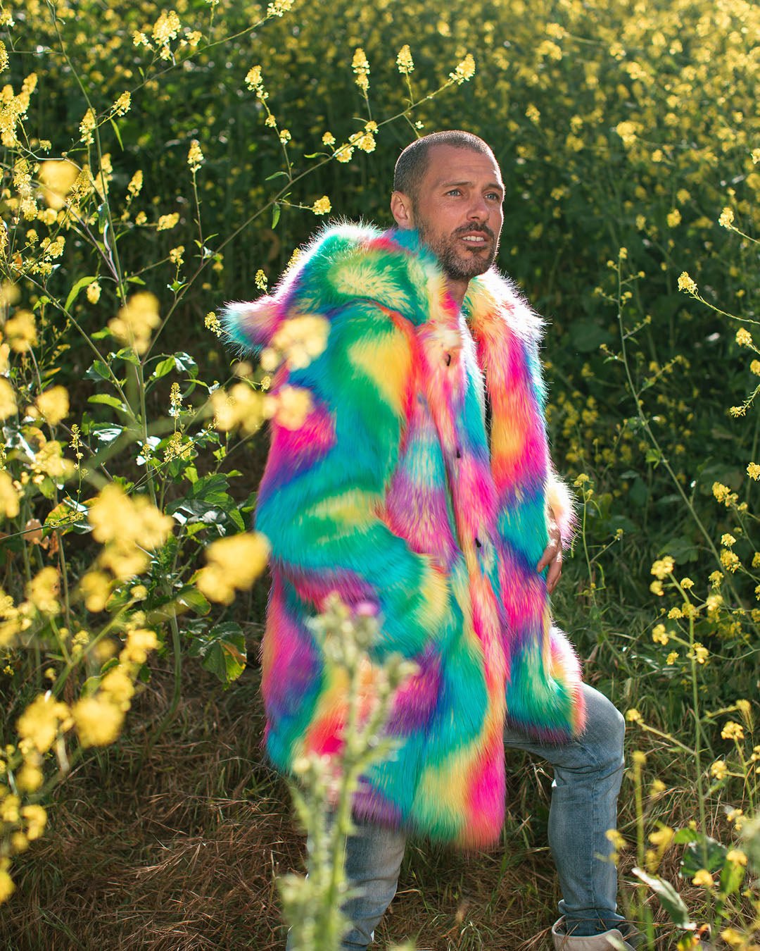 Sly guy wearing Rainbow Bear Classic faux fur coat with hands in pockets, hood, and ears up.