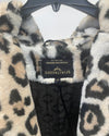 A close-up of a leopard print faux fur jacket by Spirithoods, featuring a black and beige pattern with a black embroidered lining and a black brand label.