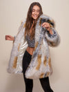 Girl with long light brown hair wearing a vegan Arctic Fox Classic coat with the hood and ears down, making a twisting motion with her body.