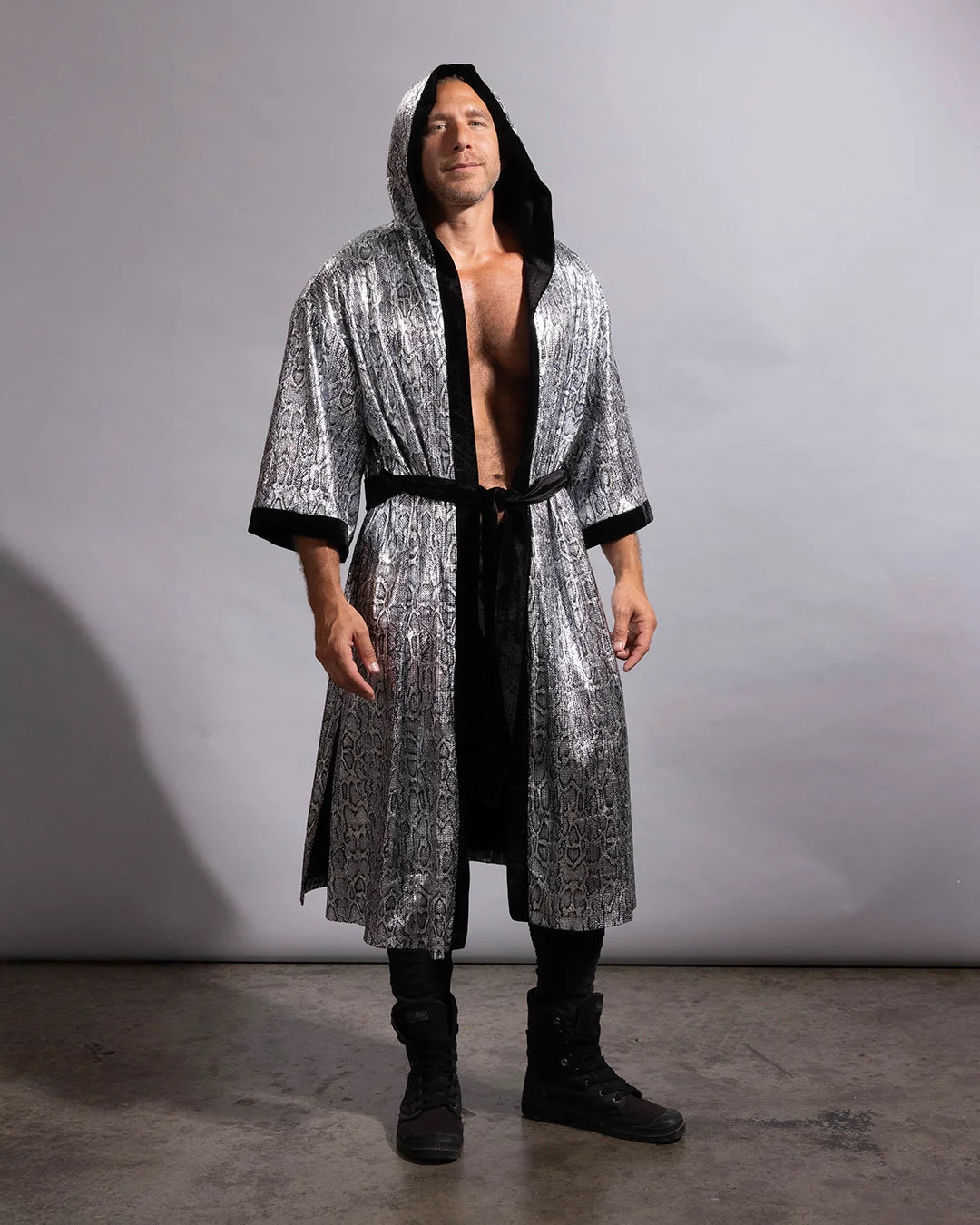 A man wearing a long, hooded kimono robe with a silver and black metallic snakeskin pattern, black lining, and a black waist tie, standing against a gray studio backdrop.