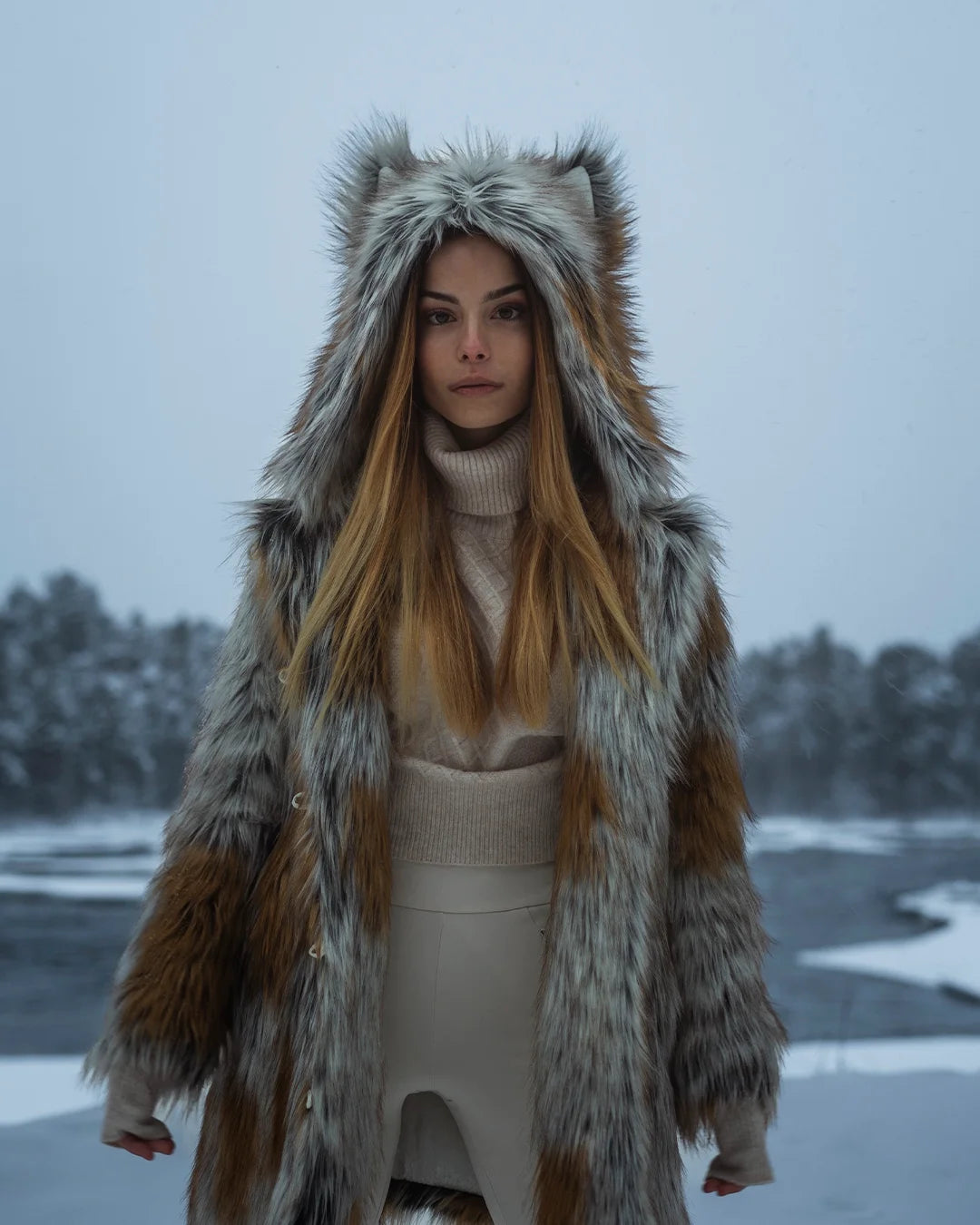A Woman wearing a SpiritHoods Arctic Fox Fake Fur Jacket with an oversized hood and ears, in a snowy landscape