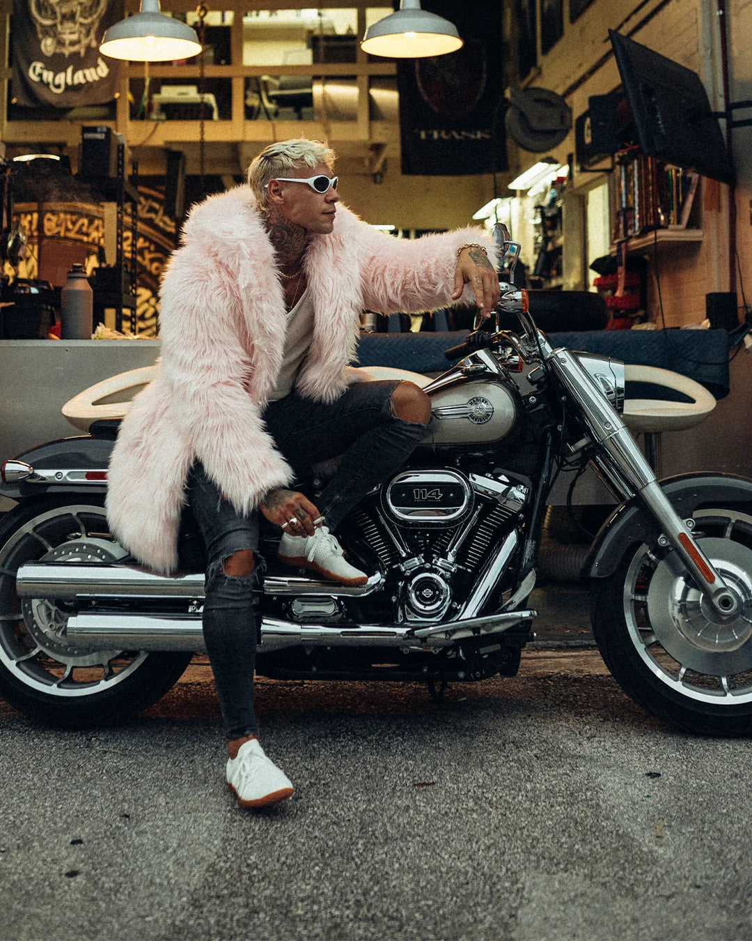 a Man on a motorcycle leaning forward, wearing spirithoods best selling pink faux fur jacket in pink flamingo. 100% Vegan Fashion Brand