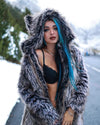 Woman wearing a Grey Wolf Classic Fake Fur Coat with a large oversized hood on, showing the distinct SpiritHoods Wolf ears on top, with a snowy background