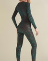 A woman with her hands to the side wearing a green animal print full-body bodysuit.