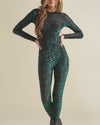 A woman with her hands on her hips wearing a green tiger print full-body bodysuit with a white background.