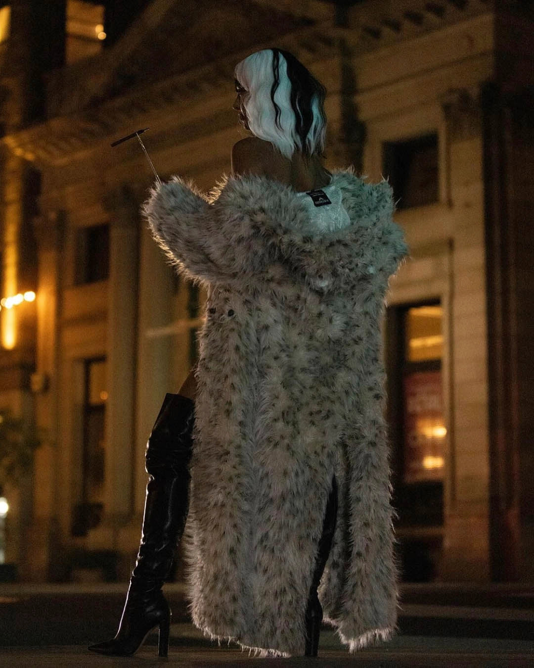 A Woman dressed as cruella deville looking away from the camera, wearing SpiritHoods Long Baby Snow Leopard Classic Floor Length Fake Fur Coat. Easy Halloween Costume Ideas. Halloween Outfits for Women