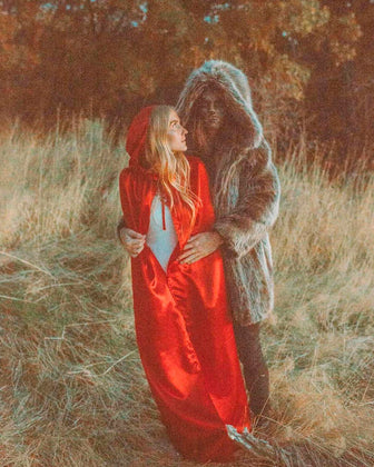 A Man dressed as the WOLF from Little Red Riding Hood, holding a woman in a red cape, while he wears the SpiritHoods Grey Wolf Hooded Coat, with the Hood Up and light wolf make up - Easy Halloween Costume Outfits and Men's Halloween Costumes