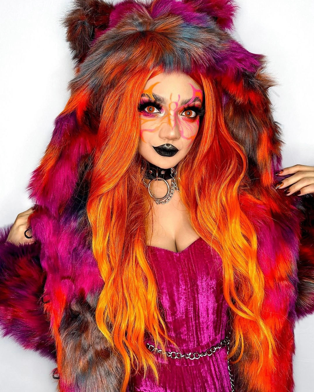 Person with vibrant orange and pink hair wearing a colorful SpiritHoods Calico Cat Fake Fur Jacket and beautiful painted butterfly across her eyes and nose - easy halloween outfit ideas - animal themed outfits for halloween