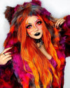 A Woman wearing SpiritHoods Collector Edition Calico Cat Fake Fur Jacket in vibrant pinks, oranges, and blues, with a orange and pink butterfly painted across her eyes and nose, that glows under UVblacklight. Easy Halloween Costume and Make Up Ideas