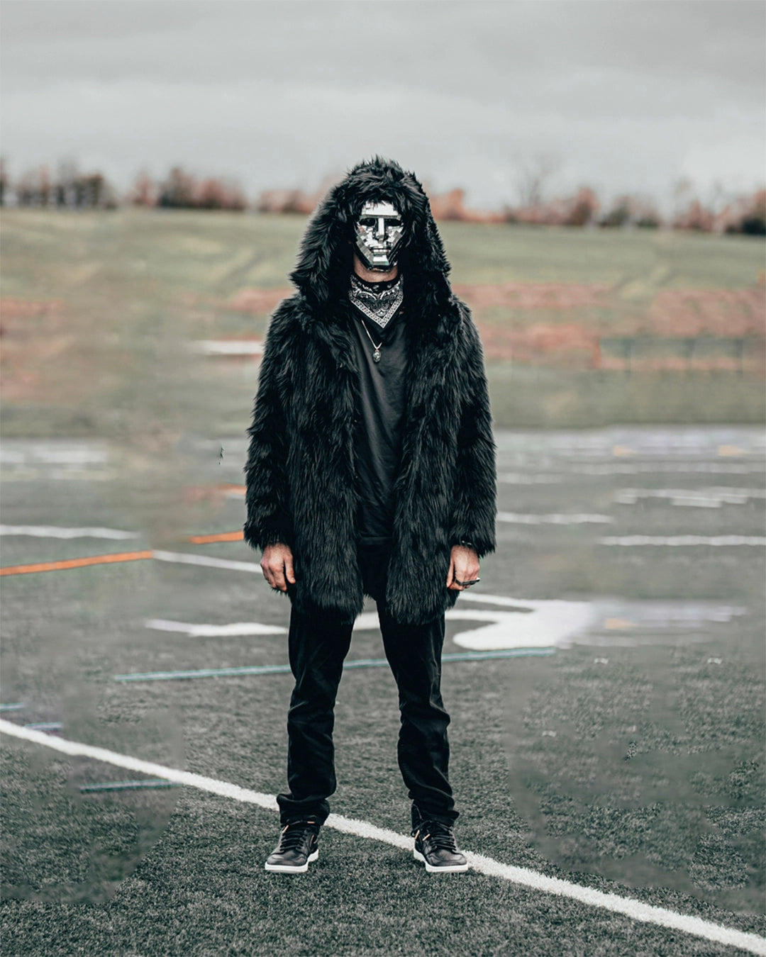 Man wearing SpiritHoods Black Wolf Hooded Faux Fur Jacket on a open field, with the hood up, wearing a mask with mirrors on it, staring at the camera. Easy Halloween Costume Ideas for Men