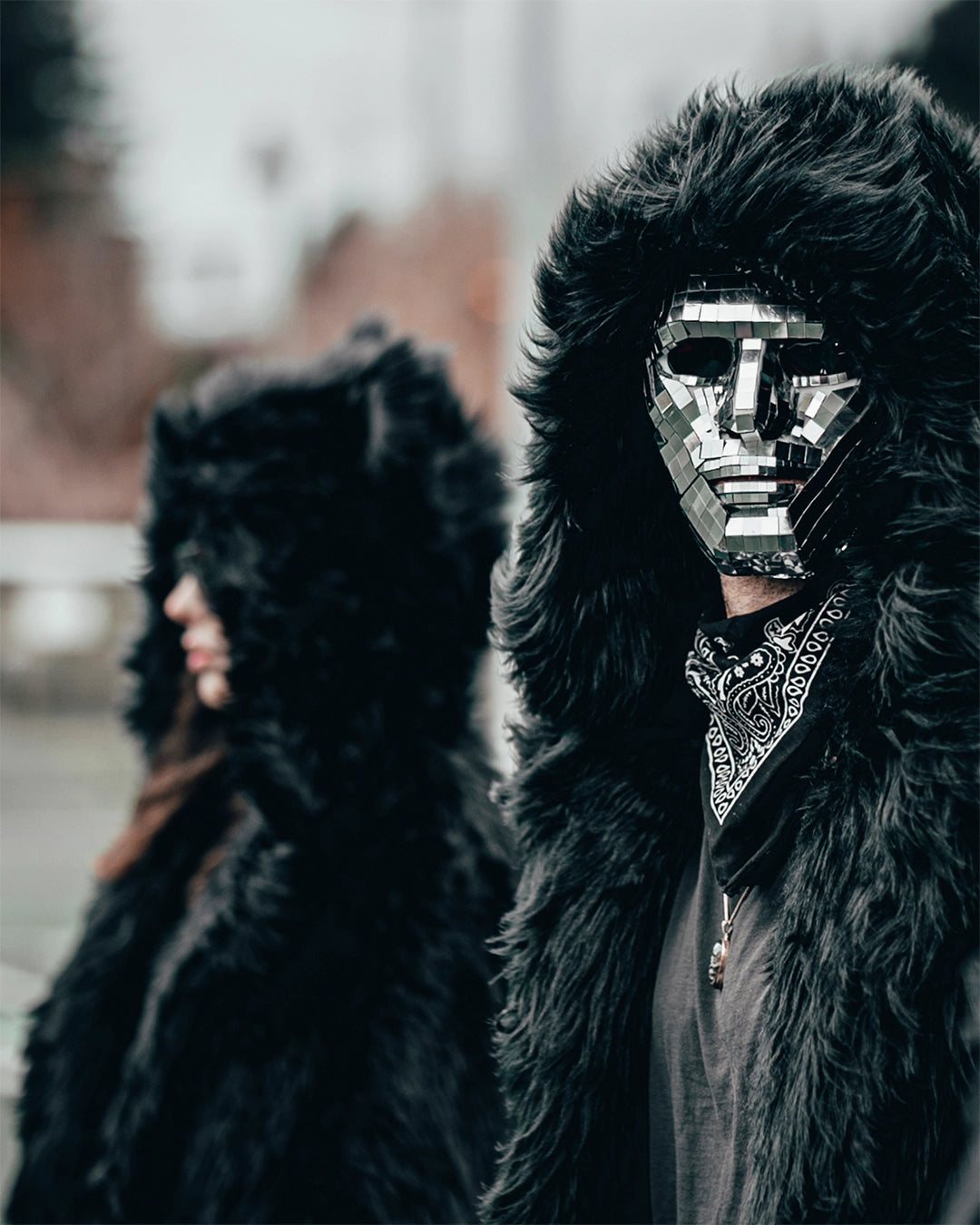 Man wearing SpiritHoods Black Wolf Hooded Faux Fur Jacket on a open field, with the hood up, wearing a mask with mirrors on it, staring at the camera. Easy Halloween Costume Ideas for Men