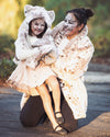 A Woman and her child, trick or treating for Halloween wearing SpiritHoods Siberian Snow Leopard Faux Fur Hood and Coat, with snow leopard face paint on both of them. Easy animal-themed costumes.
