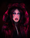 A Woman wearing SpiritHoods Black Panther Fake Fur Coat with white contact lenses in, looking at the camera with gold and black make up. The hood is up showing feline ears. Easy Halloween Make Up Ideas and Halloween Costumes.