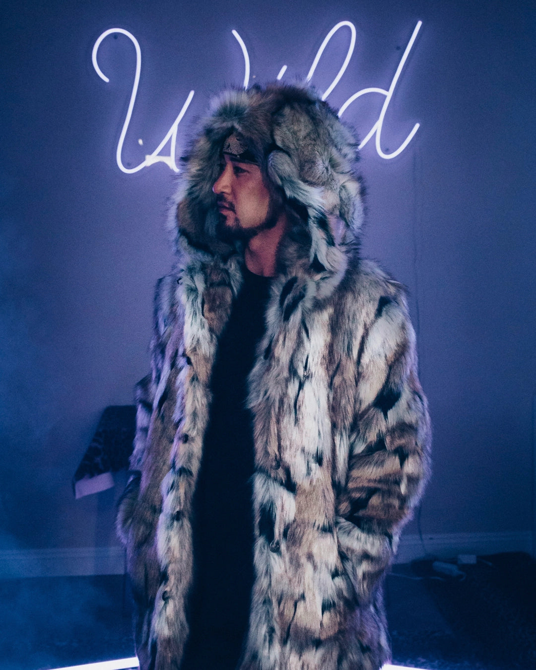 A Man wearing SpiritHoods Men's best selling wolverine fake fur coat with a neon sign in the background that says WILD..! Halloween Costume Idea for Men. Easy Animal-themed halloween costumes