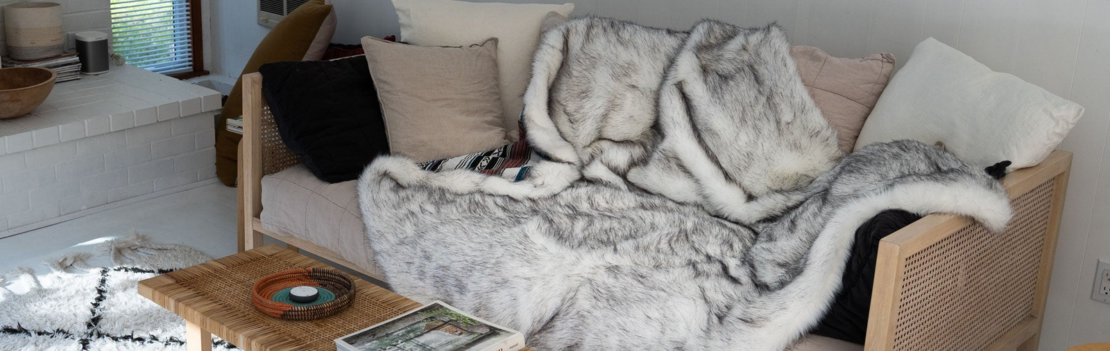Cozy living room with a sofa covered in a faux fur throw blanket, books, and a coffee table.