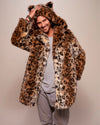 A Man smiling at the camera while wearing a leopard print faux fur coat with a hood on a plain background. SpiritHoods Made to Order Fall Winter Coat Collection. 100% Fake Fur Custom Made Jackets for Men