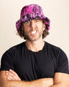 Man wearing a pink and black tiger patterned bucket hat against a beige background