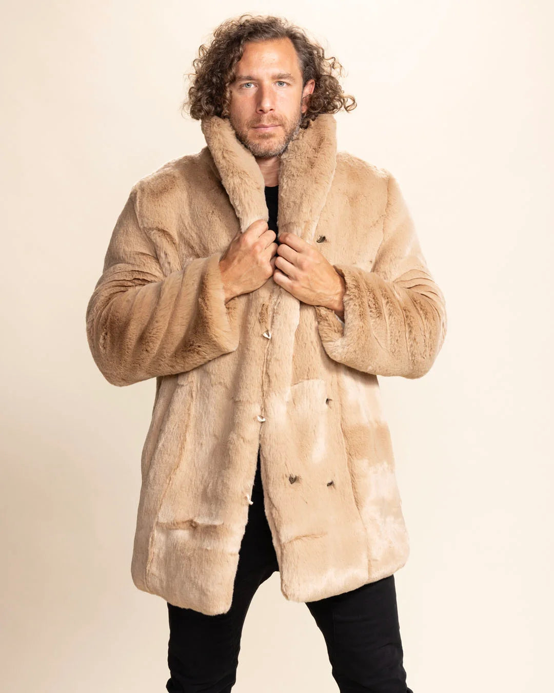 Man wearing a plush SpiritHoods beige fur free fur coat holding the oversized collar up, for a more dramatic winter layering look, show casing 8 feline face buttons down the wearer's left side, against a plain background