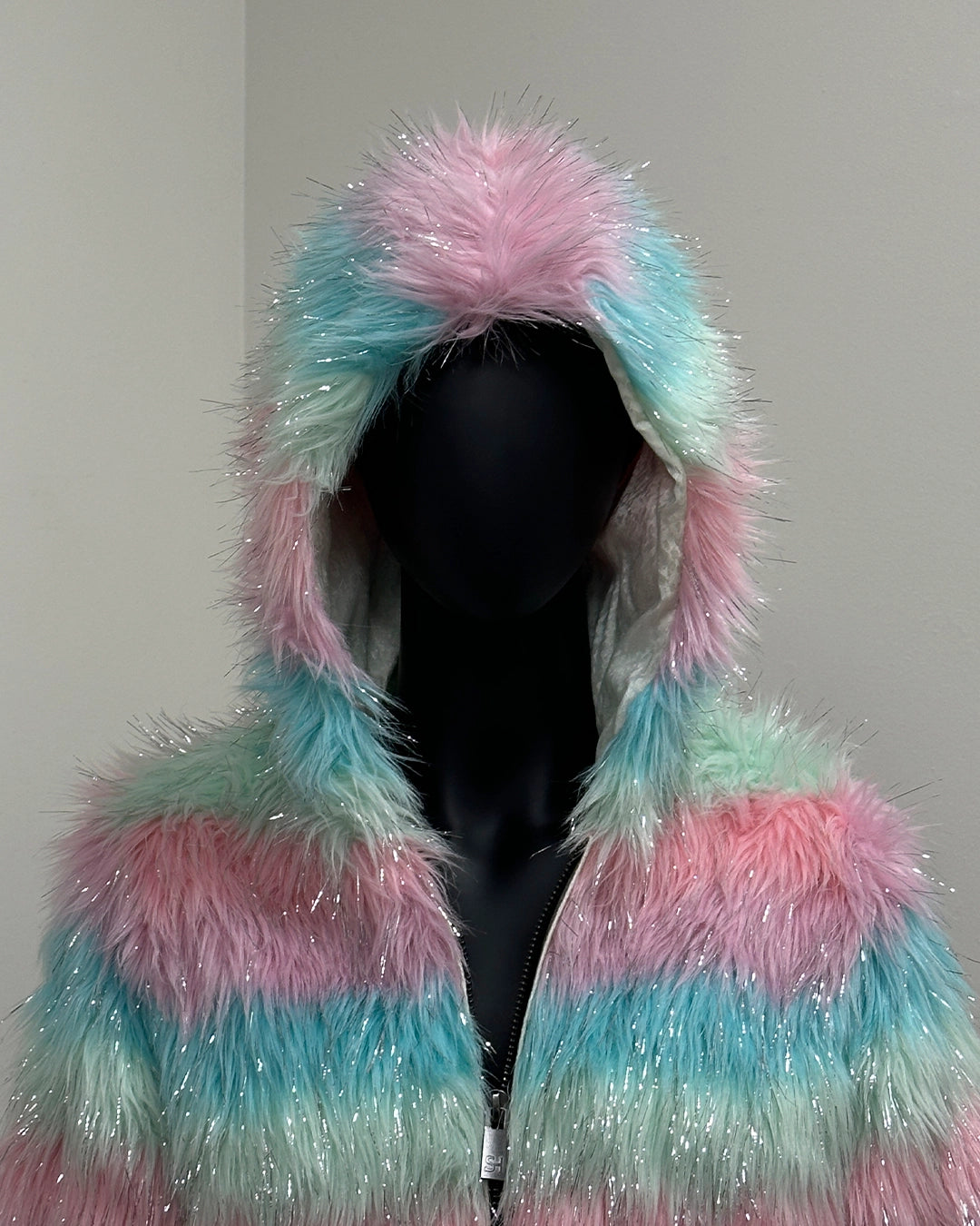 Multicolored fluffy hooded cropped jacket on a mannequin against a plain background.