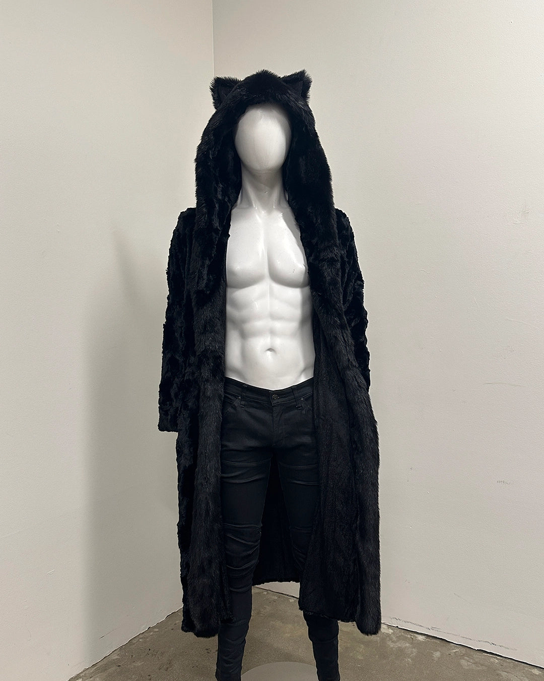 Mannequin wearing a black faux fur coat-robe with cat ears on a plain background