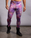 A model from the waist down wearing high-waisted rave meggings with a purple, pink, and orange leopard print pattern, paired with black boots against a gray studio background.