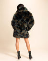 A Woman facing away from the camera, wearing SpiritHoods Camo Cat green and brown fake fur jacket, with her hands in the pockets, and the collar down. SpiritHoods Fall Coat Shop Custom Made Fake Fur Jackets.
