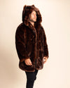 A man wearing a brown faux fur coat with plush over sized hood adorned with wolf ears on a beige background. SpiritHoods made to order faux fur coats and custom made fall winter jackets for men