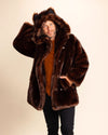A man wearing a brown fake fur coat with a hood on, and his hand against the back of the hood, and one hand in the outer coat pocket on a beige background. SpiritHoods Plush Brown Wolf Faux Fur Coat - Made to Order fall winter coat collection