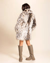 A Women wearing a cheetah pattern fur free fur coat and knee-high boots on a beige background. SpiritHoods Vegan Faux Fur Coats in Cheetah Print, Custom Made Fall Coats.