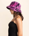 Woman wearing a pink and black animal patterned bucket hat on a beige background