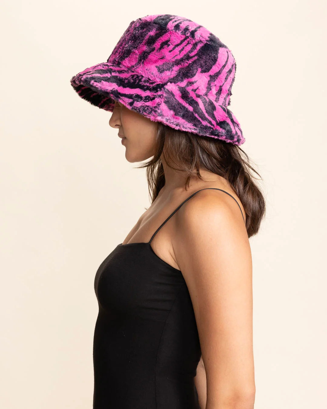 Woman wearing a pink and black animal patterned bucket hat on a beige background