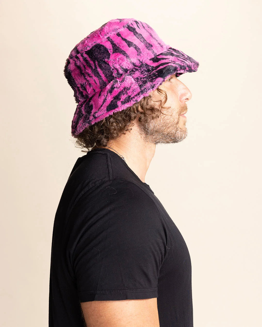 Man wearing a pink and black tiger patterned bucket hat against a beige background