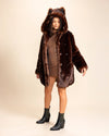 Woman wearing a brown fake fur jacket with the hood up showing the wolf ears on the top, the coat has wolf-face buttons down the side, for a peacoat closure. SpiritHoods Custom Made Faux Fur Coats and Made to Order Luxury Fake Fur Jackets
