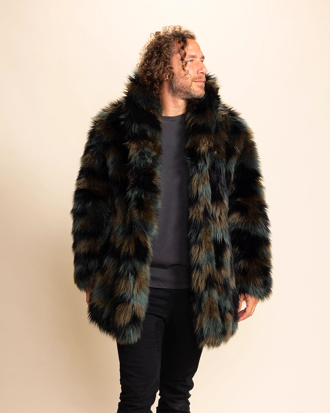 Man wearing a plush fake fur coat with greens and browns throughout, wearing the coat collar up, looking to the side smiling. SpiritHoods Fall Custom Coats and Fake Fur Jackets for Men.